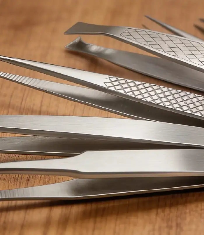 Set aus Edelstahl-Pinzetten mit unterschiedlichen Spitzen auf Holztisch, für präzise Fusspflege